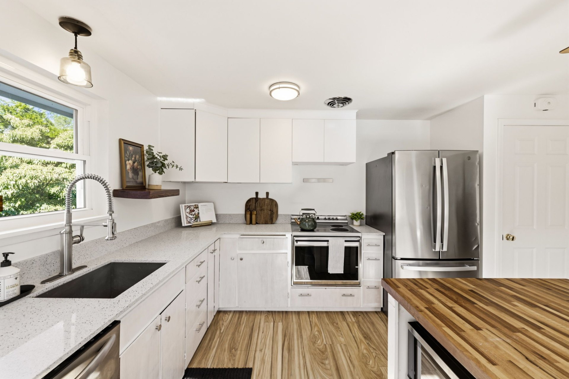 Bright kitchen with white cabinets, stainless steel appliances, and quartz countertops